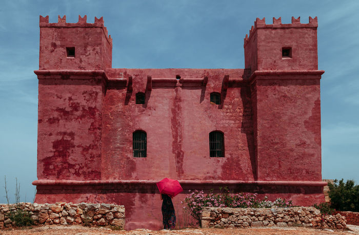REAR VIEW OF WOMAN STANDING ON PINK BUILDING