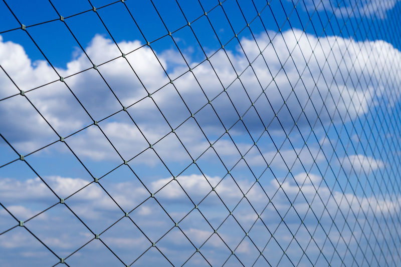 Low angle view of blue sky seen through fence