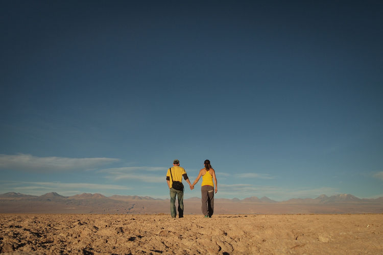 Rear view of couple in desert against sky