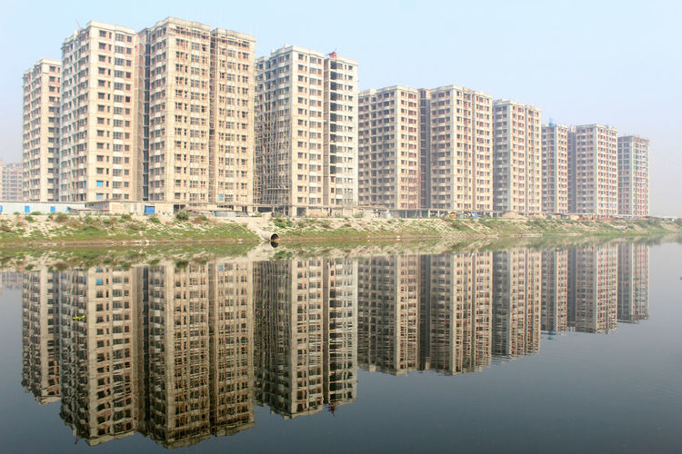 Reflection of residential buildings in lake against sky