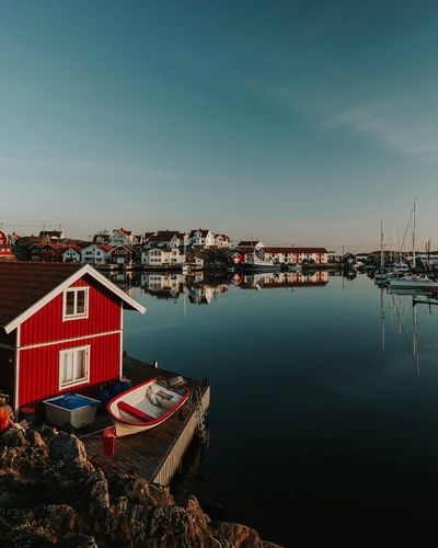 Boats moored in harbor by buildings against sky
