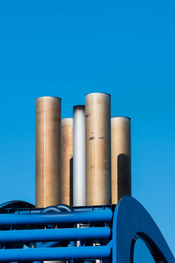 Low angle view of chimneys against clear blue sky
