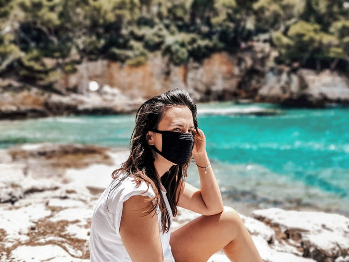 Young woman wearing black mask at beach. summer, tourism, virus, corona, covid-19.