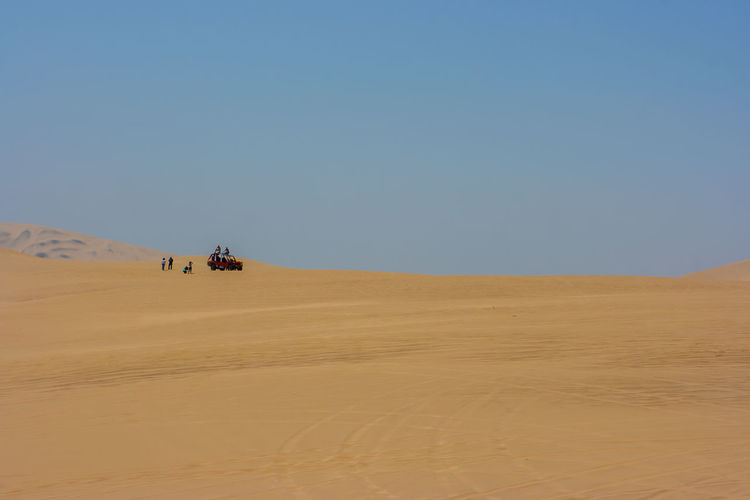 Distant view of people on desert against clear sky