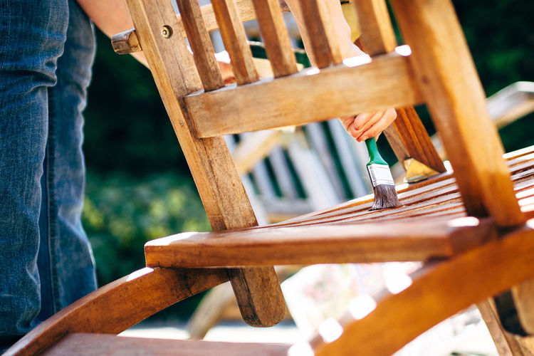 Midsection of man painting chair during sunny day