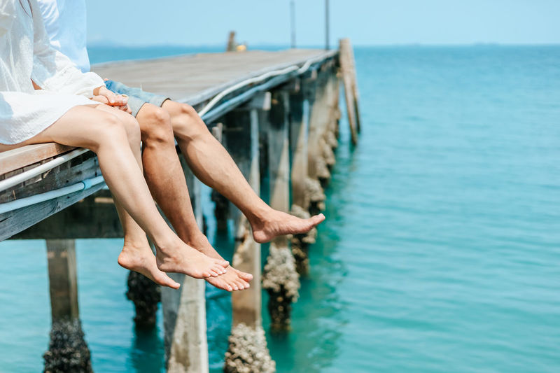 Low section of man sitting at sea shore
