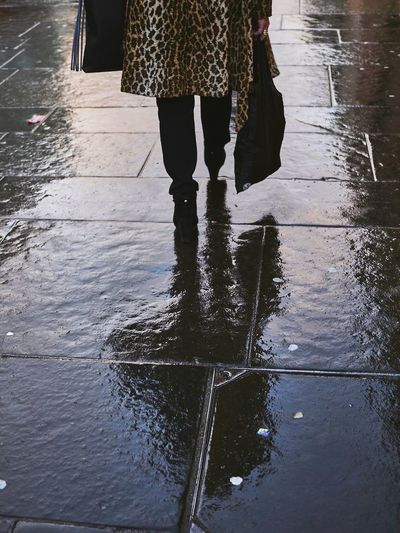 Low section of woman walking on wet footpath