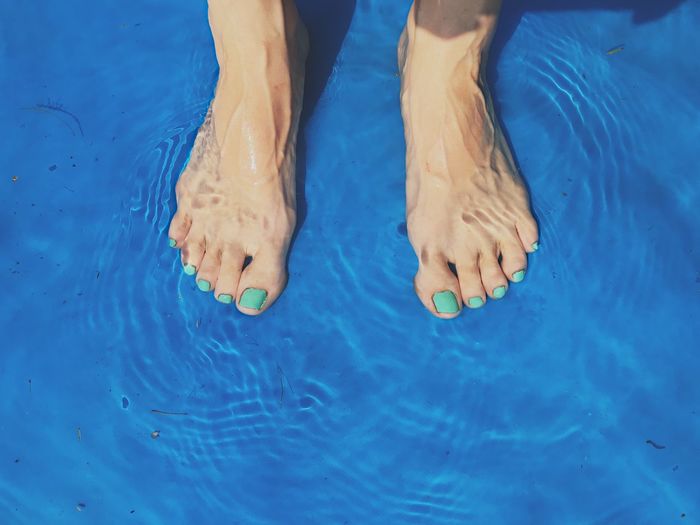 Low section of woman standing in swimming pool