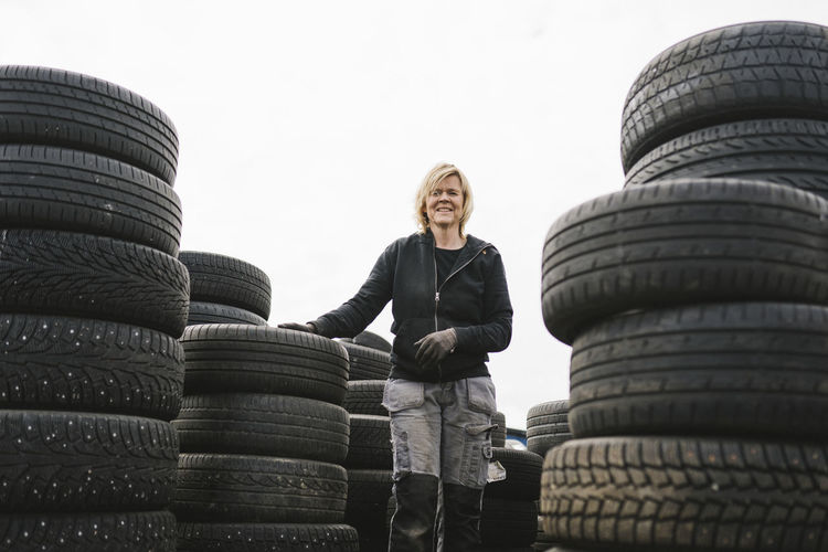 Female mechanic stacking car tires