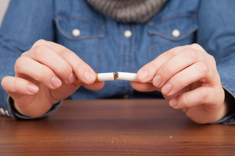 Close-up of person hands breaking cigarette over table