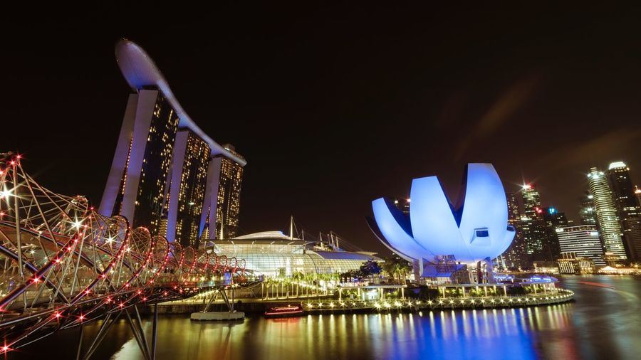 Artscience museum and marina bay sands by river in city at night