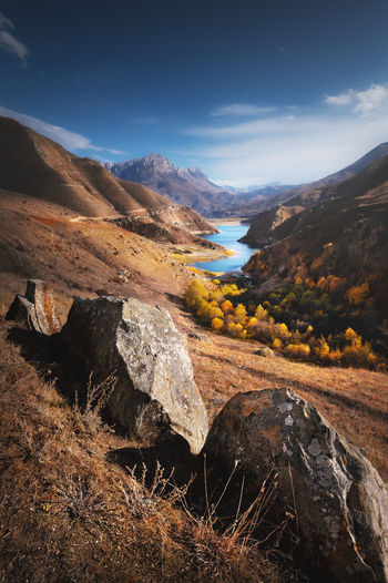 Landscape of beauty autumn day in mountain lake with stones at the front. vertical view of epic