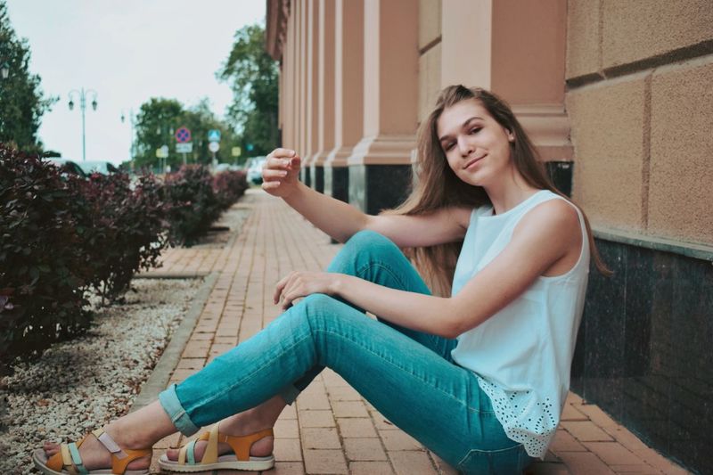 Full length of cute smiling girl sitting outdoors