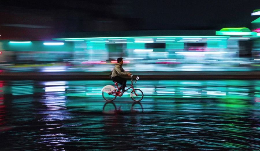 Man riding bicycle on street at night