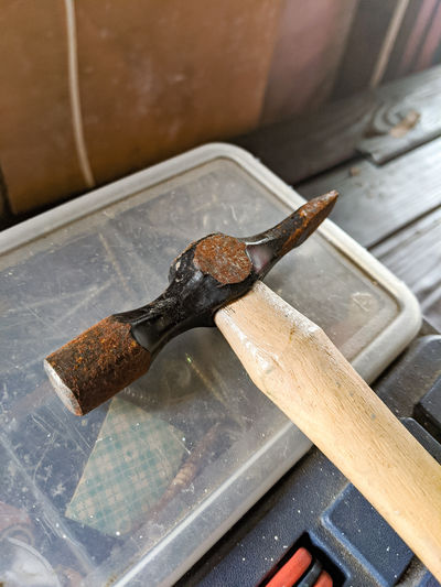 A small hammer on top of a toolbox on a wooden bench
