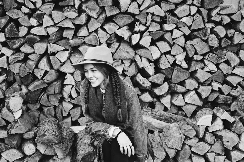 Smiling young woman sitting by logs