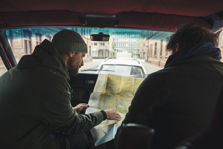 Male friends examining map while sitting in camping van during road trip
