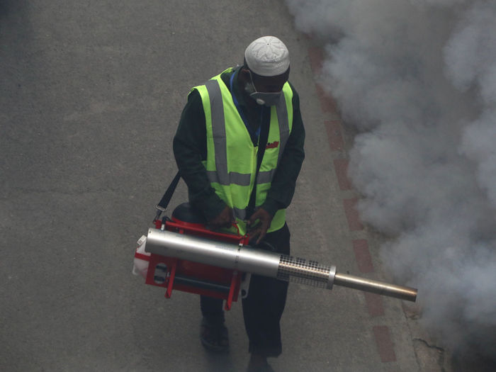 High angle view of worker spraying smoke on street