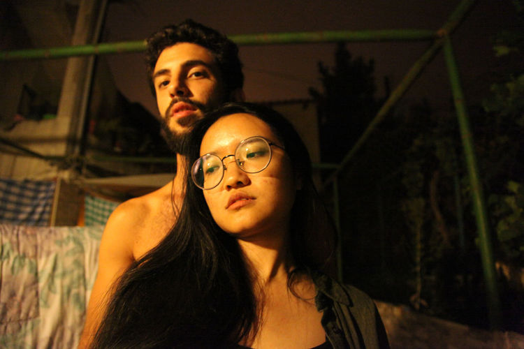 Portrait of man with woman standing outdoors at night