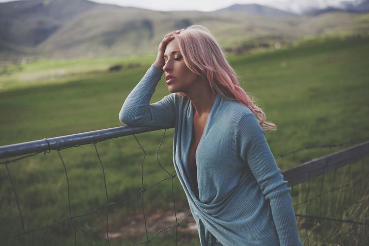 Beautiful young woman standing by field