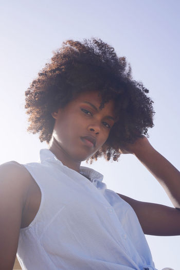 Low angle muted colors portrait of a young black woman with afro hair