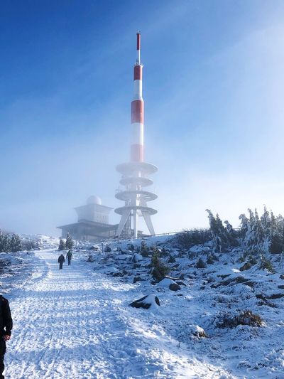 View of communication tower on snow covered land against sky