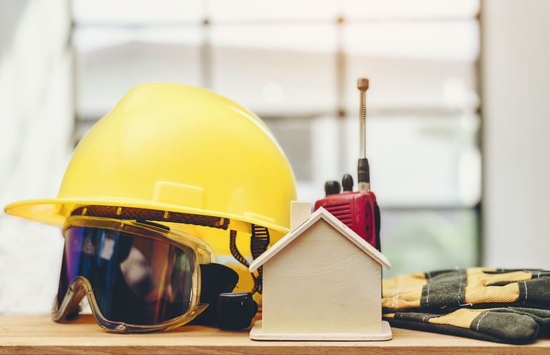 Close-up of protective workwear with walkie-talkie by model home on table