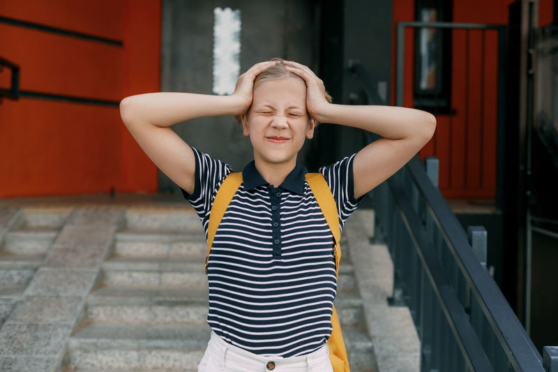 A charming schoolgirl holds her head, can't cope with stress and emotions