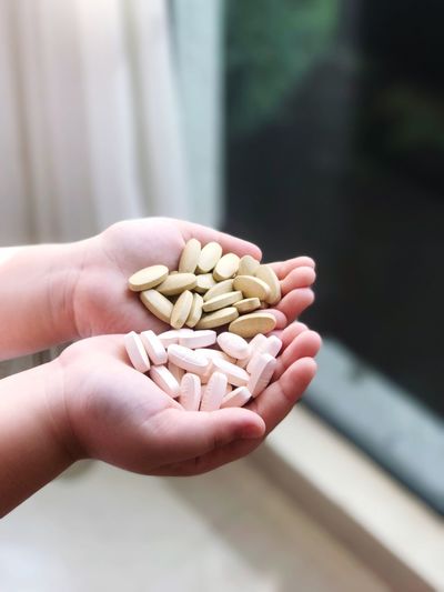 Cropped hands of child holding pills