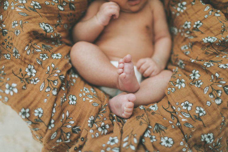 Low section of baby on bed at home