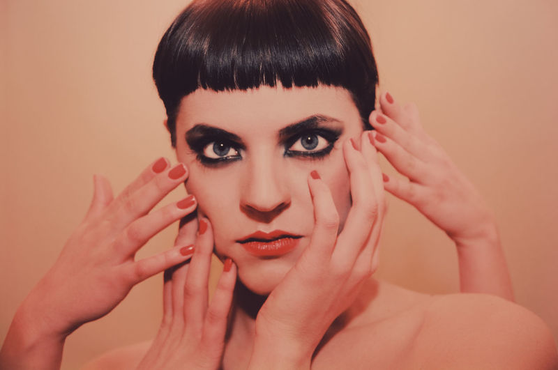 Close-up portrait of woman against beige background