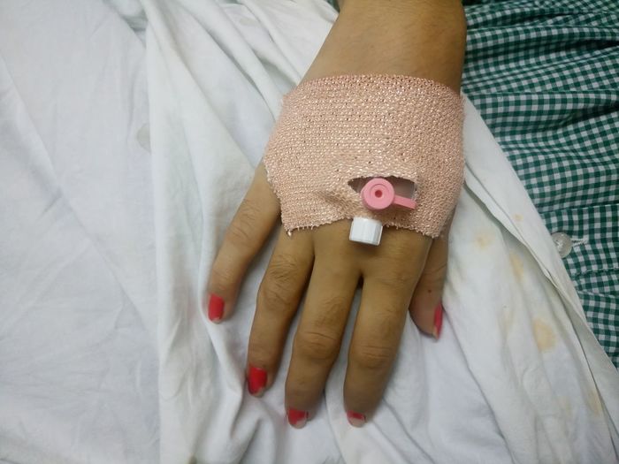 Cropped image of woman with iv drip on hand at hospital