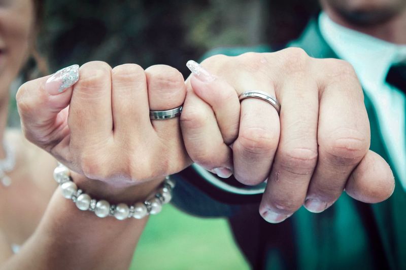 Midsection of bride and bridegroom holding hands