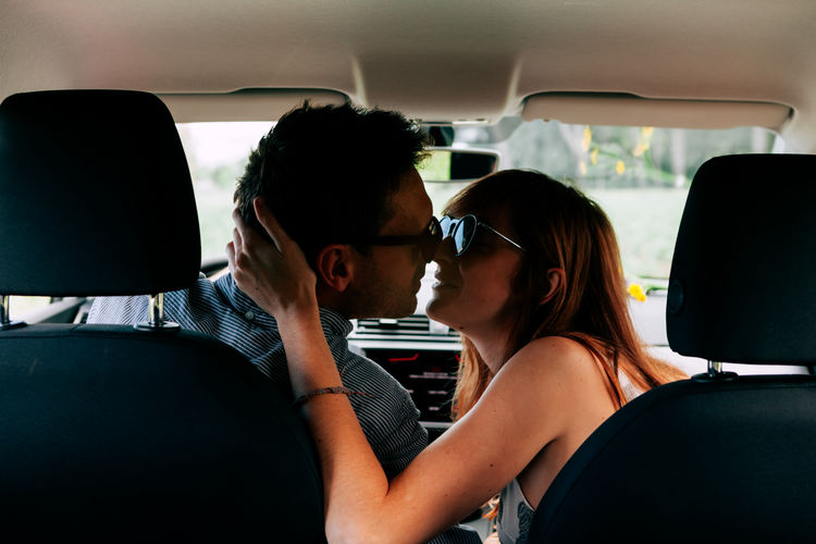 View from the back seat of lovers kissing inside car. romantic, travel, bonding concept.