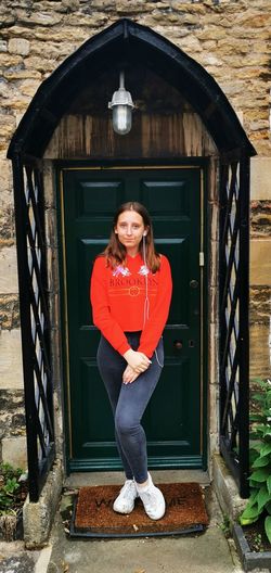 Portrait of young woman standing against door