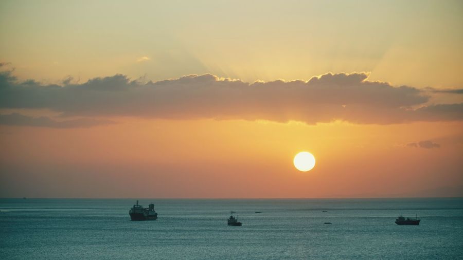 Silhouette boats on sea against sky during sunset