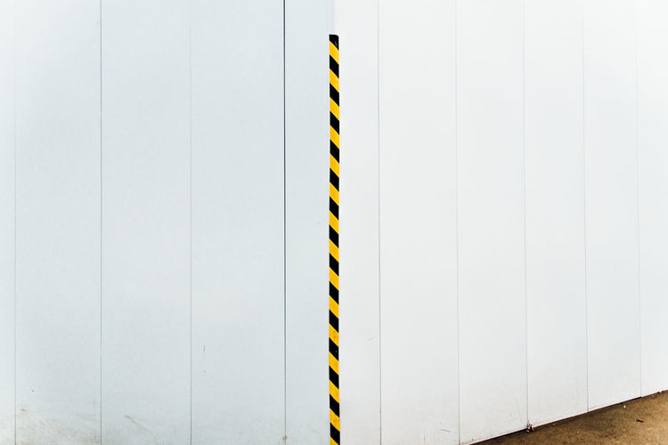 Striped pole against white wall
