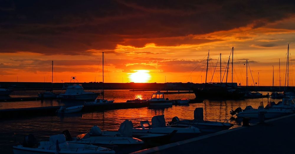 Boats moored at harbor during sunset