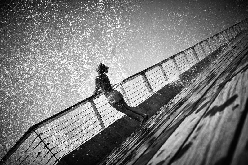 Woman enjoying water splash while standing on boat deck