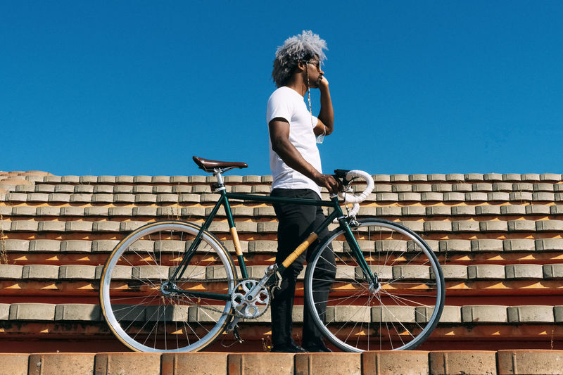 Afro and black man carrying the bike on some stairs. black rider concept. cycling in the city.