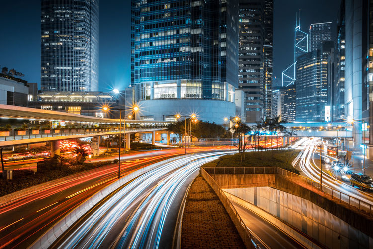 Light trails on road amidst buildings in city at night