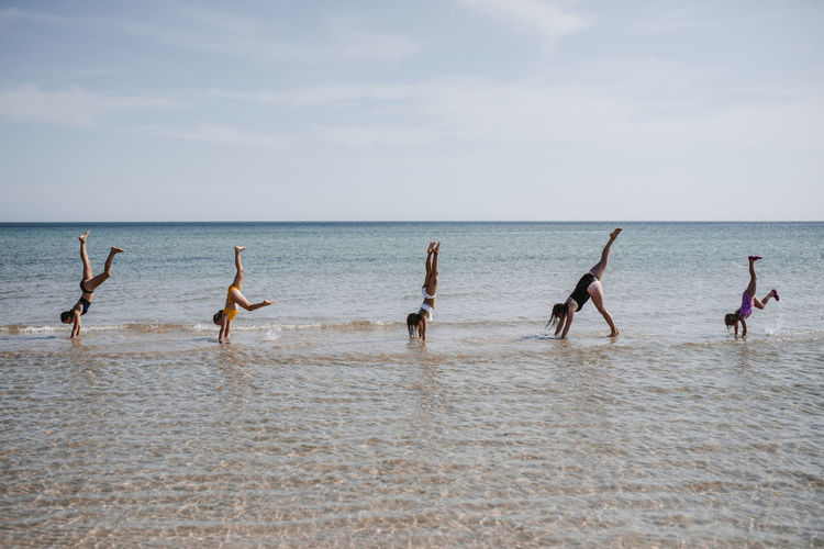 Mother with daughters doing handstand at sea