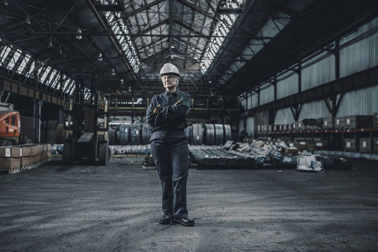 Portrait of confident female worker with arms crossed standing in metal industry