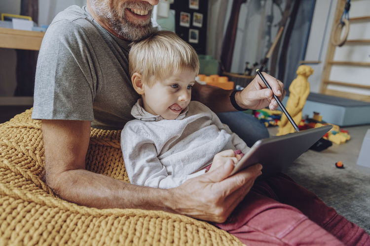 Father assisting son with e-learning on tablet at home