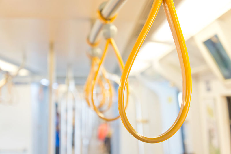 Close-up of yellow handles hanging in metro train