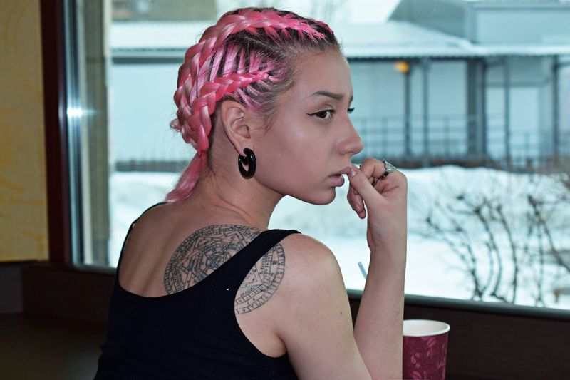 Close-up of young woman with pink hair sitting in cafe