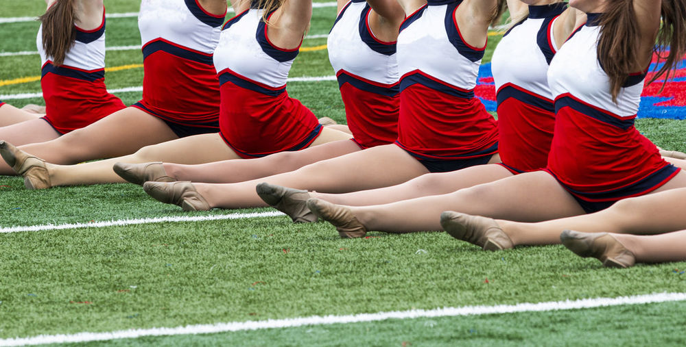 Low section of cheerleaders standing on grass