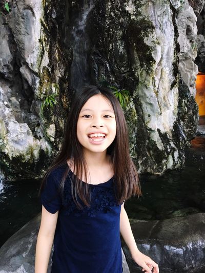 Portrait of smiling girl standing against rock formation