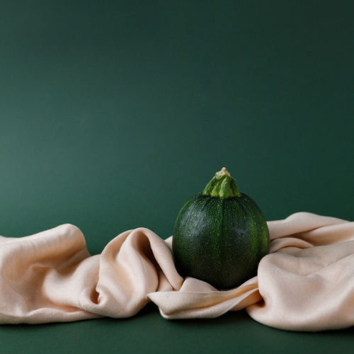 Autumn concept of zucchini on a green background with saten fabric cloth.