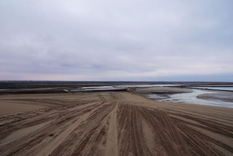 Scenic view of desert against cloudy sky